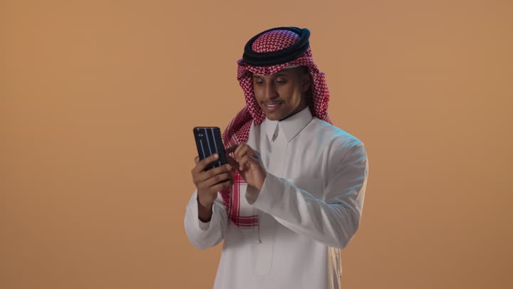 رجل سعودي يستخدم الهاتف الذكي في الاستوديو