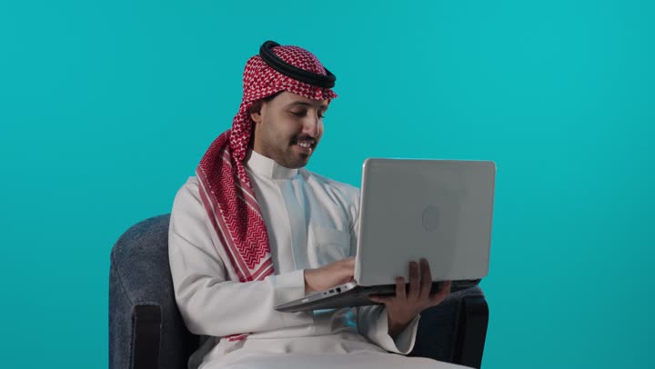 رجل سعودي بالزي التقليدي يستخدم المحمول خلفية زرقاء