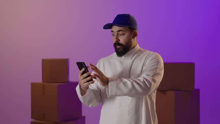 Saudi Man Using Smartphone with Shipping Boxes