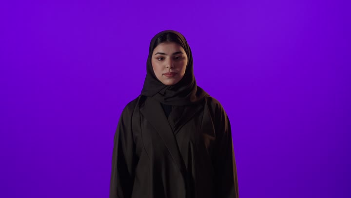 امرأة سعودية بالعباءة السوداء تقوم بإيماءة التوقف