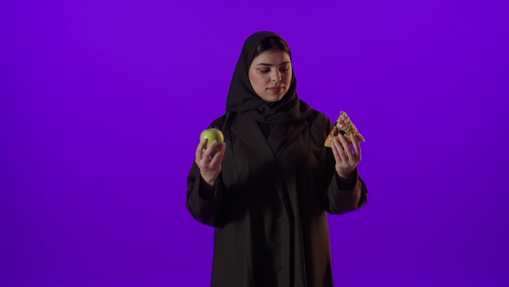 امرأة سعودية تقارن بين التفاح الصحي وقطعة البيتزا