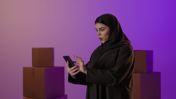 امرأة سعودية تستخدم الهاتف مع صناديق تجارة إلكترونية