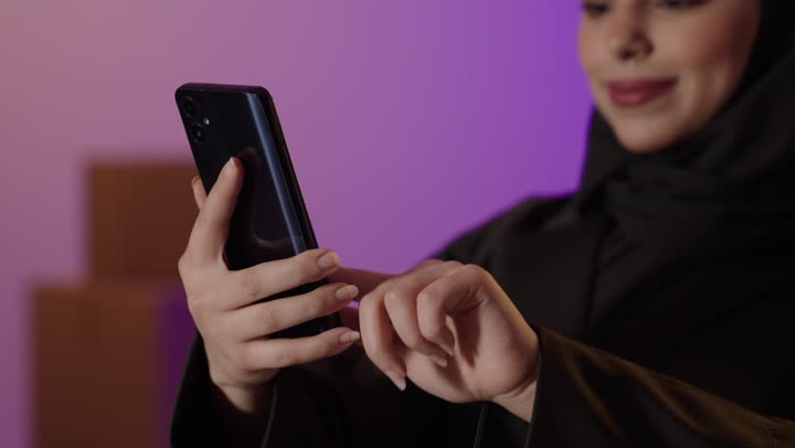 امرأة سعودية تستخدم الهاتف الذكي مع صناديق شحن