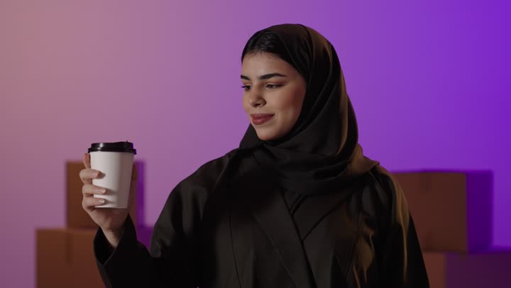 امرأة سعودية تحمل حقائب تسوق وكوب قهوة