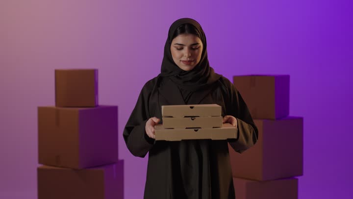 امرأة سعودية تقدم صناديق توصيل في الاستوديو