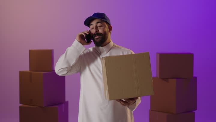 رجل توصيل سعودي يتحدث بالهاتف مع صندوق شحن