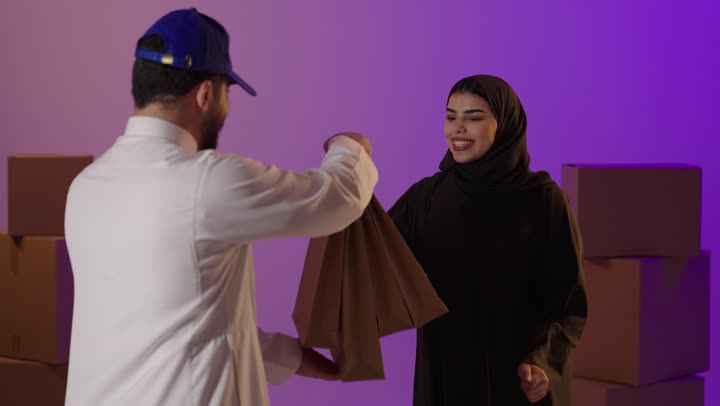 مندوب توصيل سعودي يسلم أكياس تسوق لامرأة