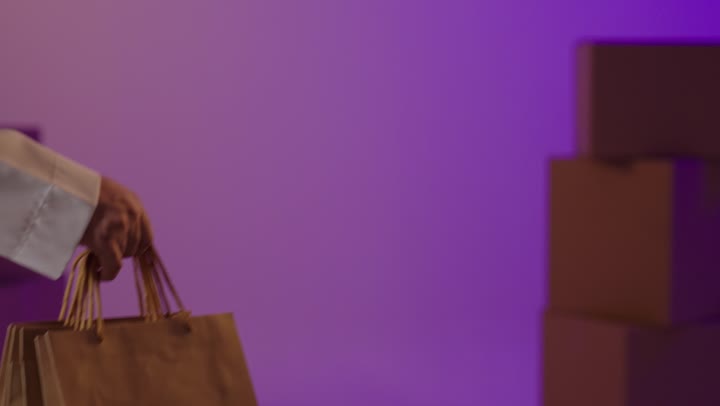 رجل يسلم حقائب تسوق ورقية في استوديو