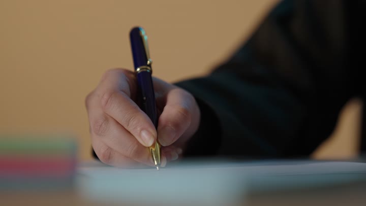 Close-up Hand Writing with Blue and Gold Pen