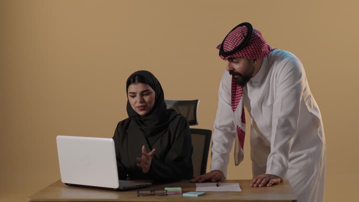 زملاء عمل سعوديون يناقشون البيانات على الكمبيوتر
