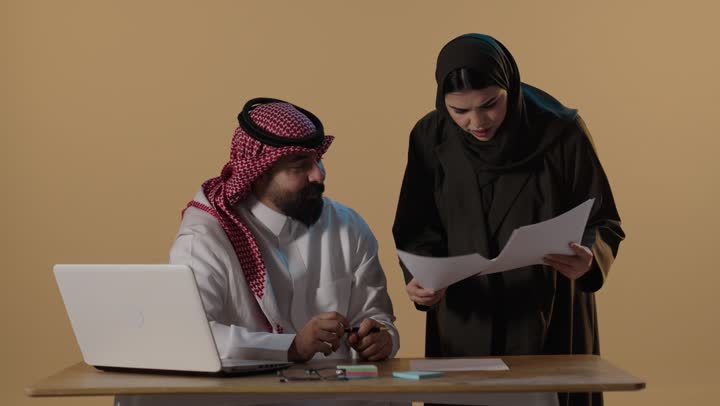 Saudi Colleagues Reviewing Office Documents at Desk