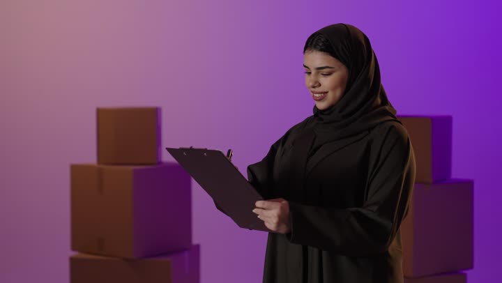 امرأة سعودية مع ملف ورق وصناديق تصوير استوديو