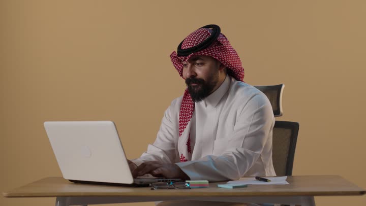 Saudi Businessman Working on Laptop in Office