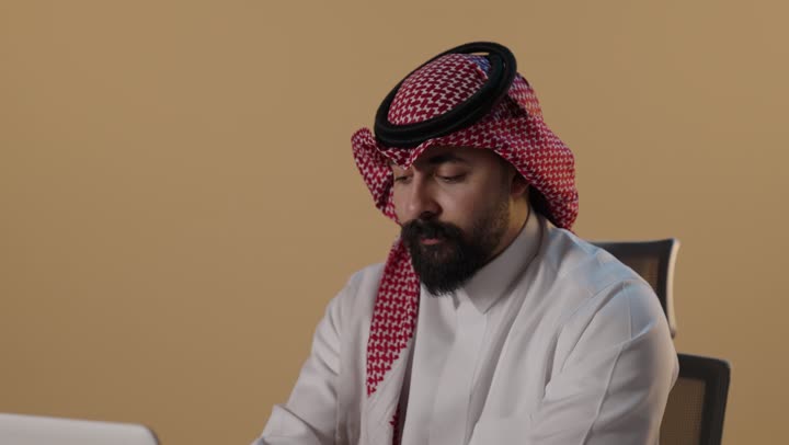رجل أعمال سعودي يكتب على كمبيوتر محمول في المكتب