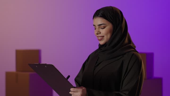 Saudi Woman Business Owner with Clipboard in Warehouse