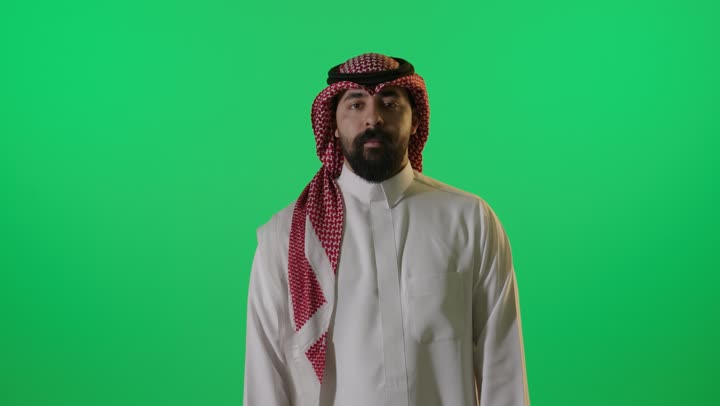 رجل سعودي يشير بعلامة الإعجاب على خلفية خضراء