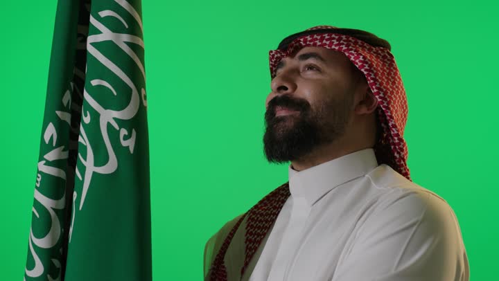 رجل سعودي مع العلم الوطني على خلفية خضراء