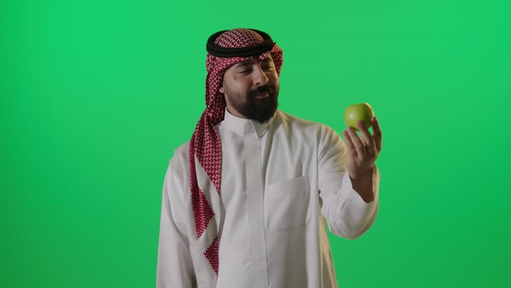 رجل سعودي مع تفاحة خضراء أمام خلفية كروما