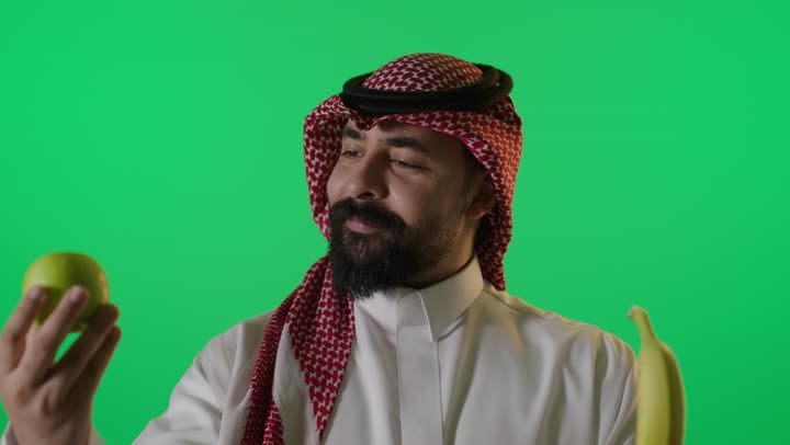 رجل سعودي يحمل تفاحة وموزة كروما خضراء
