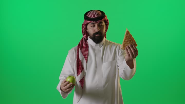 Saudi Man Choosing Healthy Apple Over Pizza Green Screen