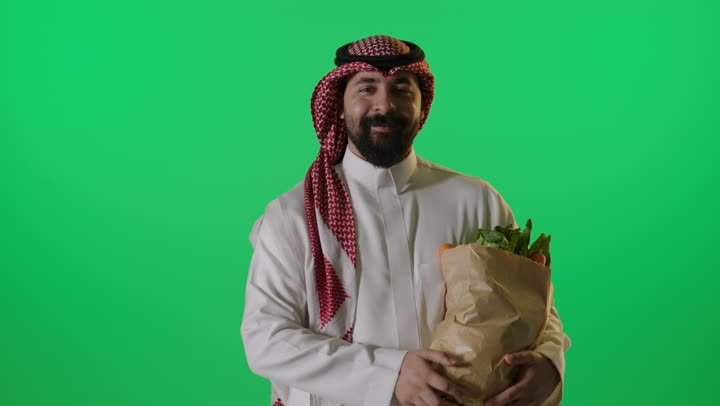 رجل سعودي يحمل كيس خضروات خلفية كروما خضراء
