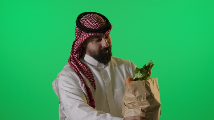 رجل سعودي يحمل حقيبة بقالة كروما خضراء