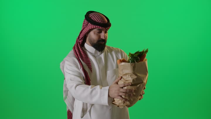 رجل سعودي يحمل حقيبة خضروات كروما خضراء