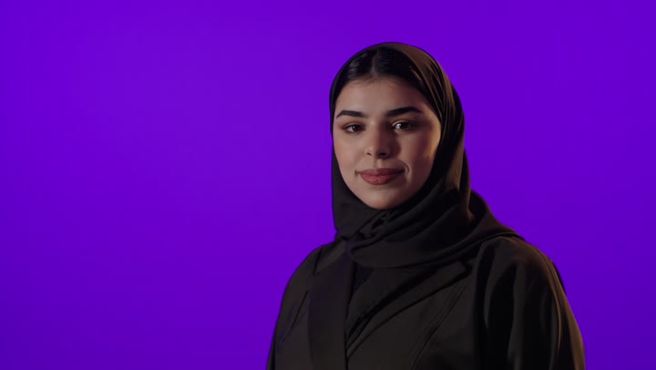 Saudi Woman in Abaya Smiling on Purple Background