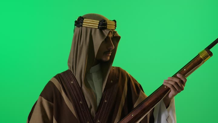 رجل سعودي باللباس التراثي مع بندقية شاشة خضراء