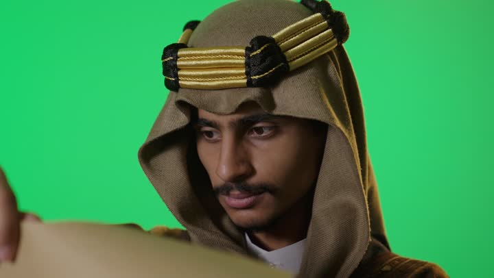 رجل سعودي بزي يوم التأسيس يقرأ وثيقة على كروما خضراء