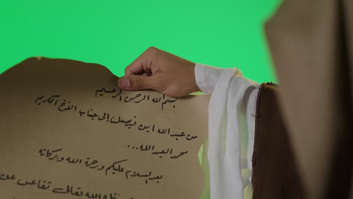 رجل سعودي يمسك مخطوطة عربية قديمة شاشة خضراء