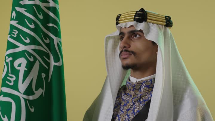 رجل سعودي بملابس يوم التأسيس التقليدية مع العلم