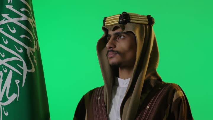 رجل سعودي بالزي التقليدي أمام خلفية خضراء