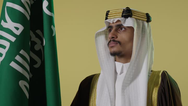 رجل سعودي بالبشت التقليدي مع العلم الوطني