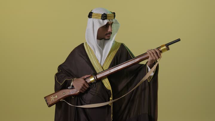 رجل سعودي يرتدي الزي التقليدي ويحمل بندقية تراثية قديمة