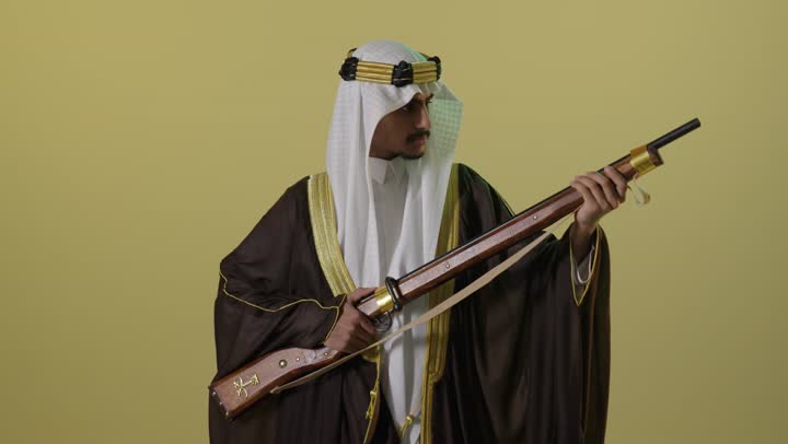 رجل سعودي بالبشت التقليدي يحمل بندقية تراثية