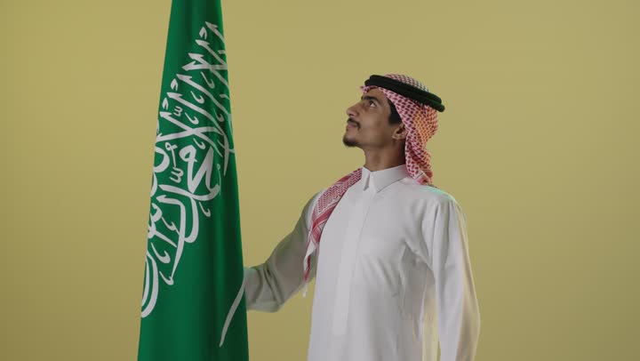 رجل سعودي مع العلم الوطني في يوم التأسيس