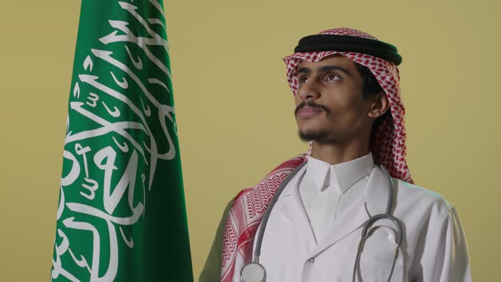 Saudi Male Doctor Standing by Saudi Flag Studio Shot