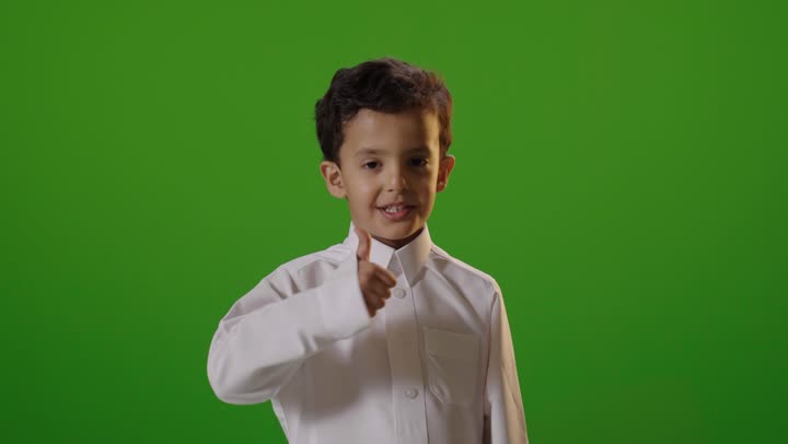 طفل سعودي يشير بالإبهام خلفية خضراء