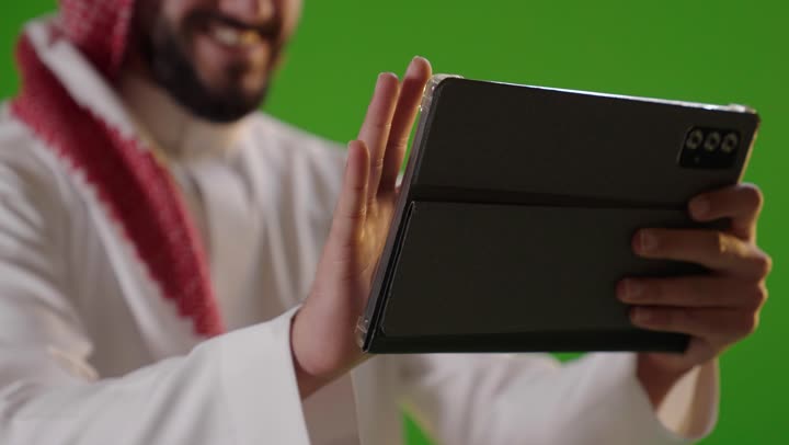 رجل سعودي يستخدم جهاز لوحي بخلفية شاشة خضراء