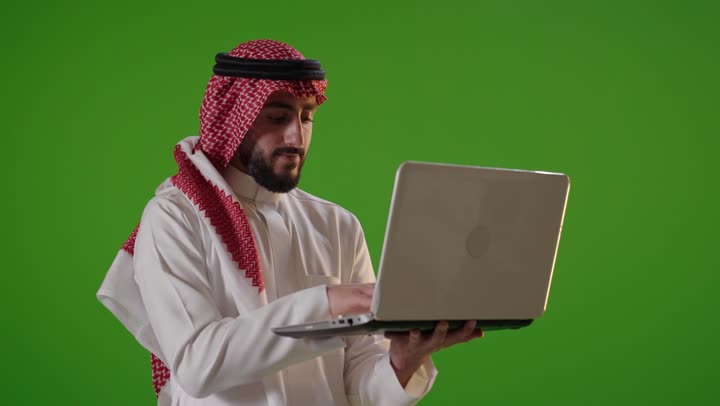 رجل سعودي يستخدم الكمبيوتر المحمول خلفية خضراء