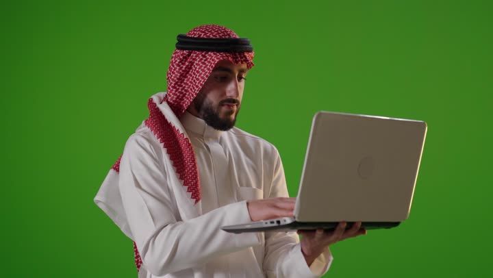 رجل عربي يكتب على كمبيوتر محمول خلفية خضراء كروما