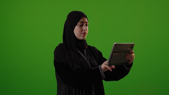 امرأة سعودية تستخدم جهاز لوحي على خلفية خضراء