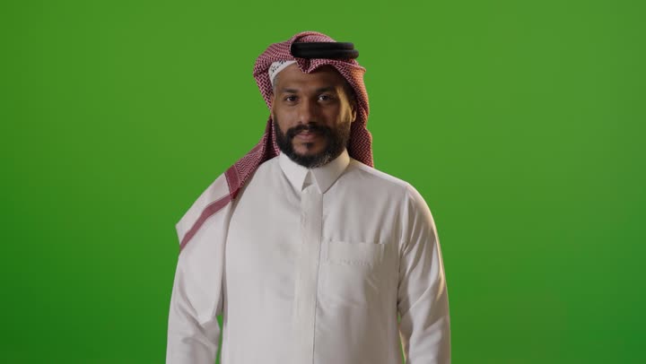 رجل سعودي يشير بعلامة عدم الإعجاب خلفية خضراء