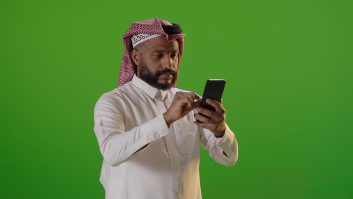 رجل سعودي يستخدم الهاتف الذكي على خلفية خضراء