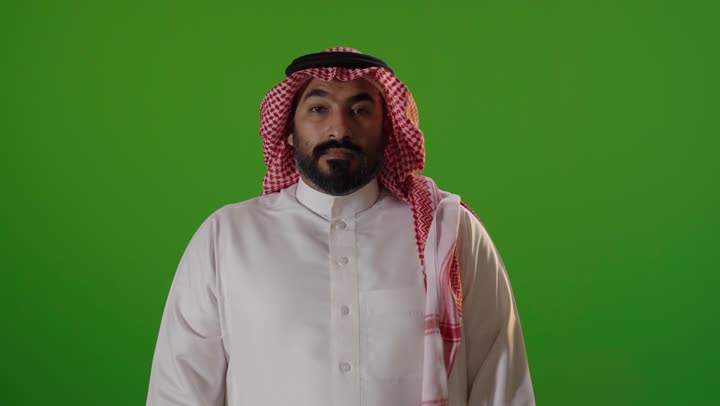 رجل سعودي أمام كروما خضراء يؤدي إشارة توقف باليد استوديو