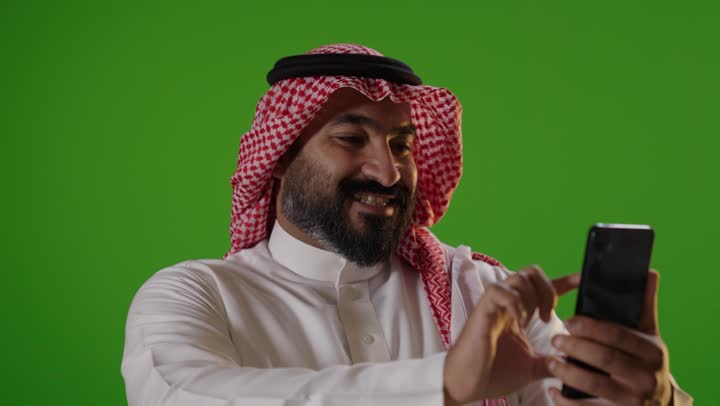 رجل سعودي يستخدم الهاتف الذكي بخلفية كروما خضراء