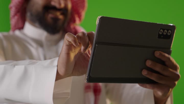 Saudi Man Using Digital Tablet on Green Screen Background