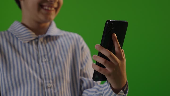 طفل يستخدم هاتف ذكي أمام كروما خضراء