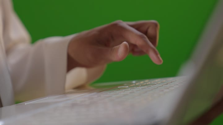 طالب سعودي يكتب على كمبيوتر محمول أمام خلفية كروما خضراء